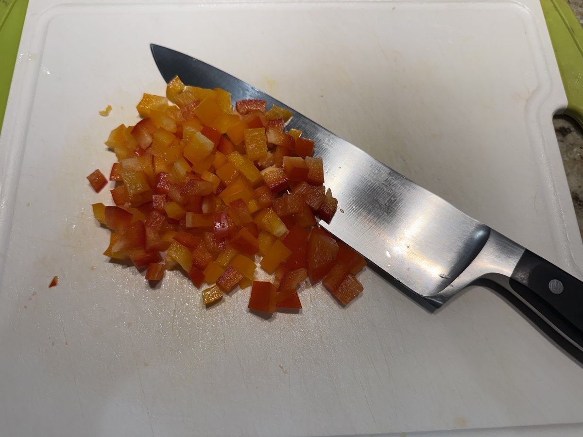 Diced bell peppers on a cutting board with a chef's knife